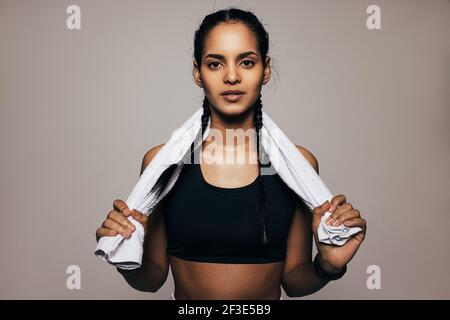 Primo piano ritratto di una donna di razza mista in abbigliamento sportivo tenendo un asciugamano bianco Foto Stock