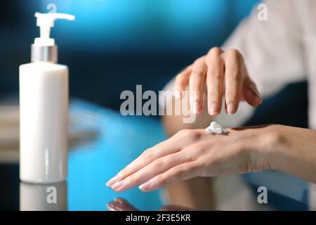 Primo piano di una donna mani che sfregano crema idratante in la notte a casa Foto Stock