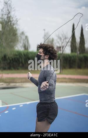 Un maschio spagnolo atletico in una maschera nera con una corda che salta Foto Stock