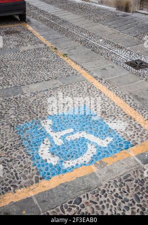 Allocato spazio per disabili su una strada acciottolata all'interno di Sassari che è una città in Sardegna Italia. Foto Stock
