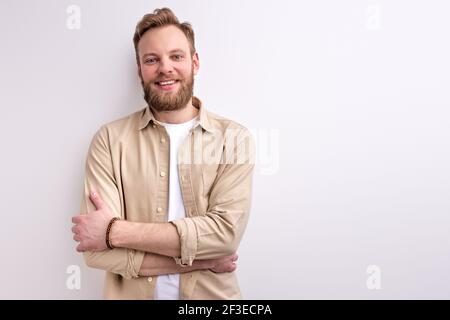 Bearded Guy in abbigliamento casual che posa a Camera avendo simpatico sorriso piacevole, in posa isolato su sfondo bianco Studio Foto Stock