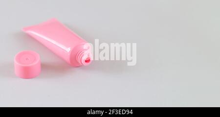 Aprire il tubo cosmetico rosa su sfondo grigio. Banner con spazio per il testo Foto Stock