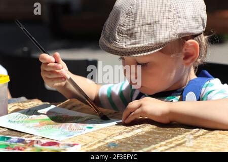 Il disegno del ragazzo con pennello e acquerelli Foto Stock