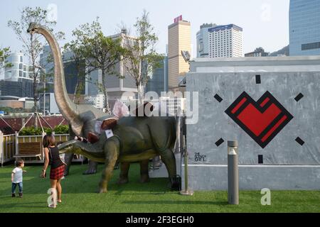 Hong Kong, Cina. 16 Marzo 2021. Una donna scatta foto con un dinosauro modello in un parco nel quartiere centrale. Una serie di nuovi casi di coronavirus (COVID-19) è emersa presso le principali banche e studi legali del distretto centrale, il centro commerciale della città, quando Hong Kong ha segnalato un picco di nuove infezioni. Credit: SOPA Images Limited/Alamy Live News Foto Stock