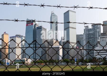 Hong Kong, Cina. 16 Marzo 2021. Una vista generale dello skyline dell'Isola di Hong Kong dietro una recinzione nel quartiere Centrale. Una serie di nuovi casi di coronavirus (COVID-19) è emersa presso le principali banche e studi legali del distretto centrale, il centro commerciale della città, quando Hong Kong ha segnalato un picco di nuove infezioni. Credit: SOPA Images Limited/Alamy Live News Foto Stock