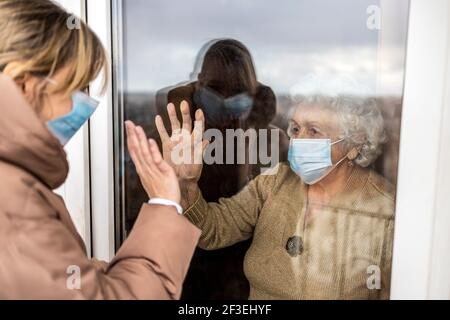 Donna che visita la nonna in isolamento durante una pandemia di coronavirus Foto Stock