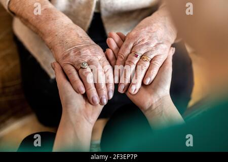 Ripresa tagliata di una donna anziana che tiene le mani con un infermiere Foto Stock