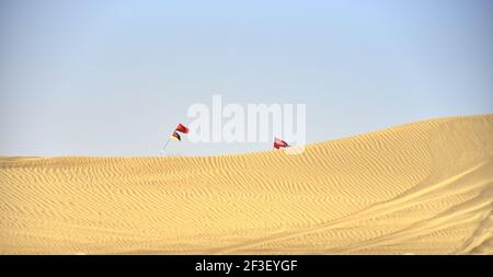 Una bella vista delle bandiere sui pali che ondolano nel deserto di al Qudra contro un cielo blu Dubai, Emirati Arabi Uniti Foto Stock