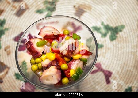 ciotola in vetro con insalata multicolore di polpo, piselli e peperoni Foto Stock