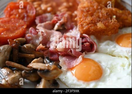 Colazione inglese tradizionale - piatto con uova fritte, fagioli, funghi, pancetta, crocchette di patate e pomodori Foto Stock