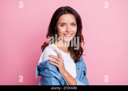 Foto di lucido affascinante giovane donna riccamente vestiti jeans abbracciandosi braccio spalla mano isolato sfondo rosa Foto Stock