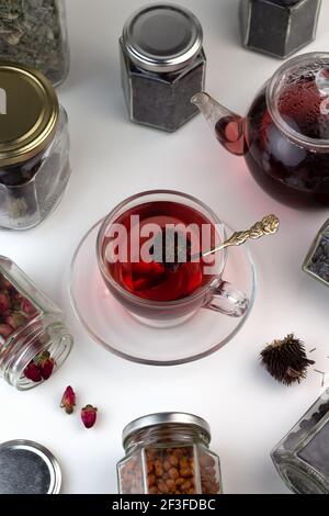 Tè alle erbe fatto in casa. Un rimedio che aumenta l'immunità e allevia lo stress. Teiera in vetro e tè con una bevanda calda e sana. Vasi trasparenti con lei asciugata Foto Stock