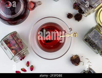 Tè alle erbe fatto in casa. Un rimedio che aumenta l'immunità e allevia lo stress. Teiera in vetro e tè con una bevanda calda e sana. Vasi trasparenti con lei asciugata Foto Stock