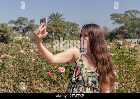 Primo piano ritratto di una giovane donna attraente che tiene un fotocamera digitale per smartphone con le mani e prendendo un selfie autoritratto di se stessa verricello Foto Stock