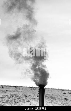 Vapore che esce da un camino di ventilazione di riscaldamento in un giorno d'inverno. Bianco e nero. Nessuna gente. Foto Stock