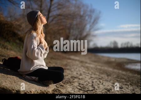 Pratica della meditazione e dell'interazione con la natura. Ragazza vicino al fiume Foto Stock