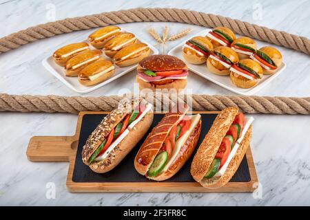 Vari panini su un banco del negozio. Sandwich con formaggio, cetriolo e pomodoro sul tagliere. Foto Stock