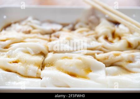 Vista laterale tradizionale cantonese cibo di cheong divertente o riso i rotoli di noodle si avvicinano alla composizione orizzontale Foto Stock