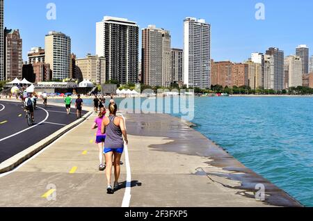 Chicago, Illinois, Stati Uniti. Con l'alto distretto di North Lake Shore Drive sullo sfondo, le persone sono attive sul Chicago Lake Trail. Foto Stock