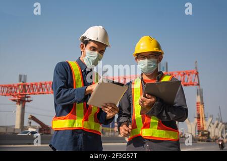 Due tablet per lavoratori ingegneri che lavorano sulla costruzione di strade in cantiere, un uomo asiatico costruttore di architettura costruire geometra professionista Foto Stock