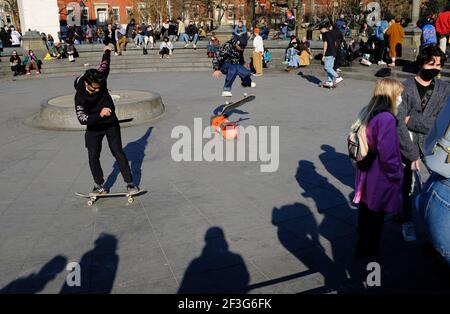 Gli skateboarders praticano abilità all'interno della fontana centrale con persone che indossano il viso Maschera raccolta intorno in una giornata di sole in Washington Square Park.New York City.USA Foto Stock