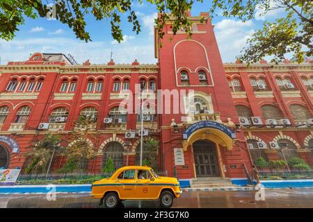 Taxi giallo di fronte al palazzo della Government Municipal Corporation costruito in stile coloniale a Kolkata, India Foto Stock