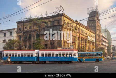 Tram e autobus pubblico sulla strada della città con vista Vecchi edifici di uffici nella zona Esplanade di Kolkata India Foto Stock