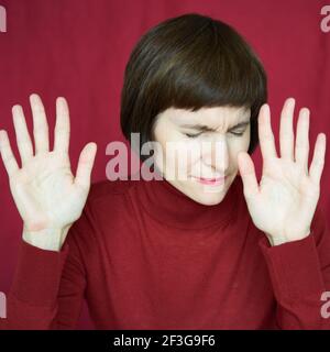 Ritratto di donna matura in difficoltà, mani in su, situazione di arresto, stop gest. Faccia tesa agitata Foto Stock