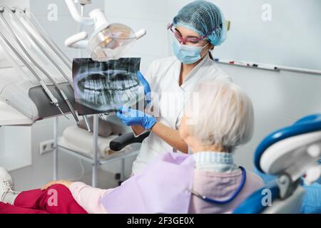 Dentista che introduce la radiografia dentale ad una donna in sedia medica Foto Stock