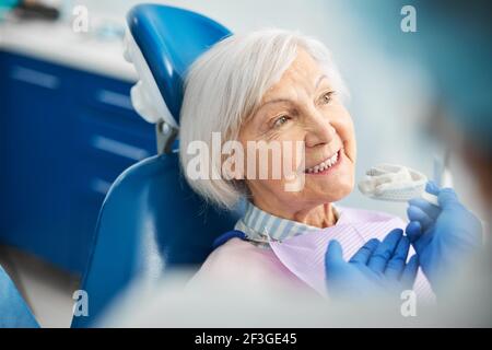 Felice femmina senior che riceve un suggerimento di silicone impronta dentale Foto Stock