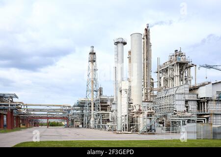 Segnalato con luci rosse, tubo fumogeno a fuoco selettivo e sferico gasholder di impianto petrolchimico di notte buio drammatico cielo lungo tempo di esposizione shot Foto Stock