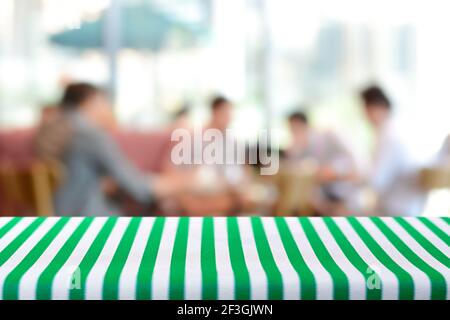 Tavolo coperto con tovaglia striata su sfondo sfocato di persone in caffetteria - possono essere utilizzati per montaggio e. mostra alimenti o prodotti Foto Stock