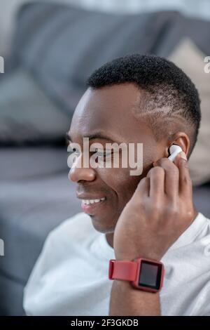 Ragazzo afroamericano in abiti bianchi che indossa auricolari wireless Foto Stock