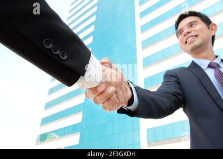 Handshake di uomini d'affari con faccia sorridente - saluto, trattare, fusione & concetti di acquisizione Foto Stock