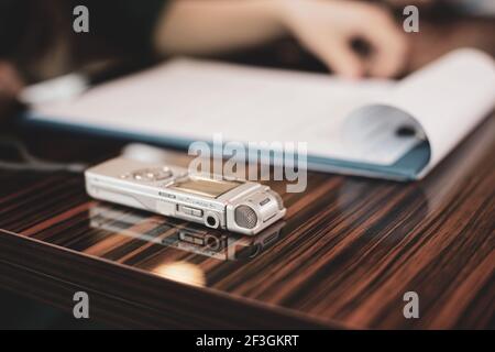 Immagine della profondità di campo poco profonda (fuoco selettivo) con un registratore audio di una giornalista donna durante un'intervista. Foto Stock