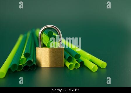 Pachlock e cannucce di plastica per bevande su sfondo verde. Eliminazione del concetto di cannucce per bevande in plastica Foto Stock