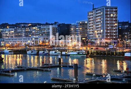 Boulogne-sur-Mer (Francia settentrionale): Barche da pesca lungo la banchina nel porto e gli edifici illuminati di notte, lungo il litorale del "cote d’Opale" Foto Stock