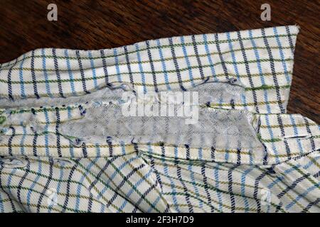 Una vecchia camicia molto amata è giunta alla fine della sua vita utile. Il materiale in cotone da cui è stato realizzato il colletto della camicia è diventato usurato e nudo. Foto Stock