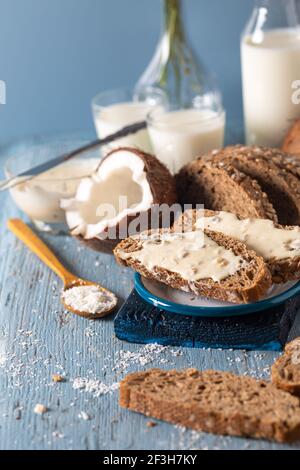 Crema al burro di cocco spalmata su fette di pane integrale con cocco fresco e fiocchi. Foto Stock