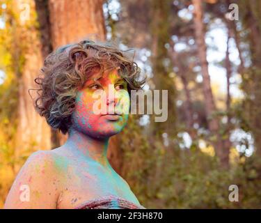 Bella donna bruna felice in posa con polvere multicolore di Holi esplodente al parco. Holi festival, persone, copia spazio. Foto Stock