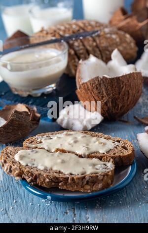 Crema al burro di cocco spalmata su fette di pane integrale con cocco fresco e fiocchi. Foto Stock