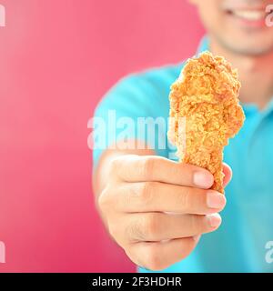 Un uomo che dà gamba di pollo fritta o bastone di pollo Foto Stock