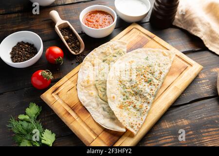 Gutab piatto nazionale azerbaigiano con carne e verdure insieme con yogurt e suma su tavola di legno Foto Stock