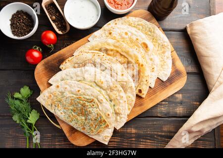 Gutab piatto nazionale azerbaigiano con carne e verdure insieme con yogurt e suma su tavola di legno Foto Stock