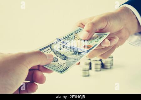 Mani che danno & che ricevono i soldi, 100 dollari USA (USD) fattura - effetto di colore vintage (retro) stile Foto Stock