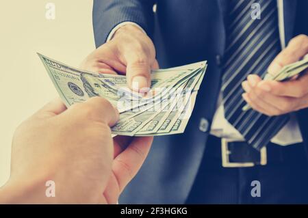 Mano che riceve denaro, dollari USA, da uomo d'affari - effetto colore vintage (retro) stile Foto Stock
