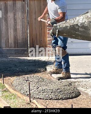 FRESNO, STATI UNITI - Mar 13, 2021: Una foto di un operaio che tovagliava il cemento mentre si riversa fuori dalla macchina sul terreno in un quartiere residenziale Foto Stock