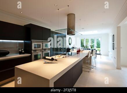 Vista della cucina minimalista/sala da pranzo con grande isola unità/bar per la colazione in una nuova costruzione di casa in Virginia Water, Surrey. Foto Stock