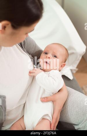 Un bambino piange nelle braccia della madre. Foto Stock