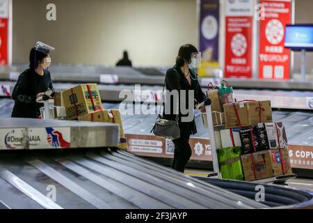 (210317) -- MANILA, 17 marzo 2021 (Xinhua) -- i passeggeri che indossano maschere di protezione sono visti all'interno del Terminal 1 dell'aeroporto internazionale Ninoy Aquino a Manila, Filippine, il 17 marzo 2021. Le Filippine hanno detto che sospenderà temporaneamente l'ingresso di stranieri e di alcuni cittadini, mentre il paese del Sud-est asiatico affronta un rinnovato picco nei casi COVID-19. In una dichiarazione rilasciata il martedì sera, la task force del coronavirus del paese ha detto che i cittadini stranieri e i cittadini di ritorno che non avevano lavorato all'estero non potranno entrare nel paese dal marzo 20 fino al 19 aprile sotto il Th Foto Stock